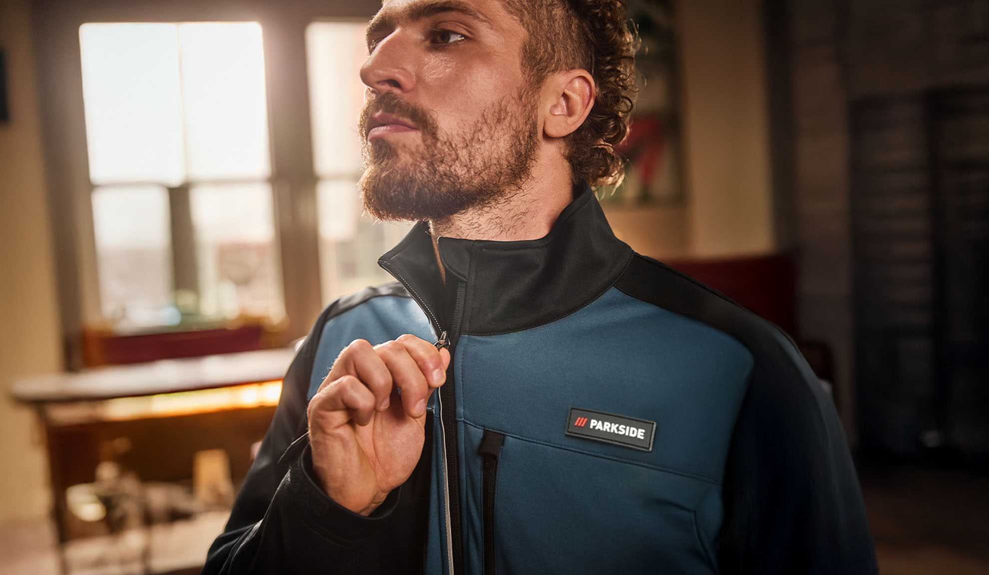 Άνδρας με μπλε και μαύρο μπουφάν εργασίας Parkside, το οποίο κουμπώνει.