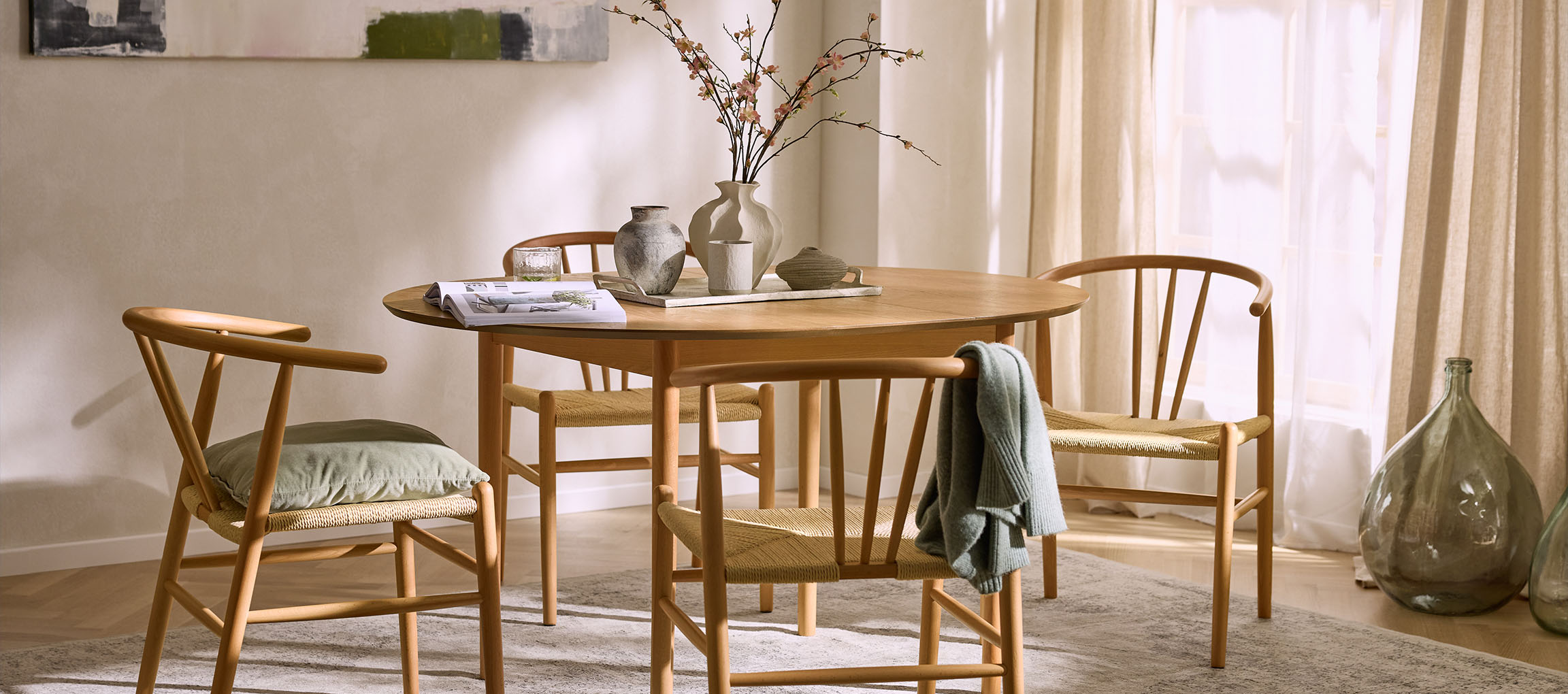 Τραπεζαρία με στρογγυλό ξύλινο τραπέζι, ξύλινες καρέκλες με ψάθινα καθίσματα και διακοσμητικά βάζα.