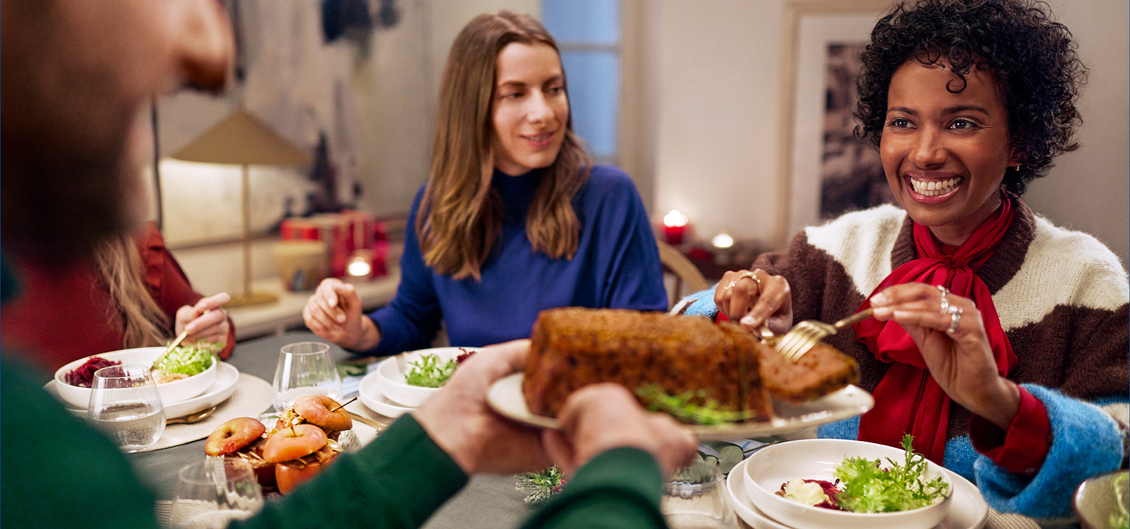 Φίλοι απολαμβάνουν ένα εορταστικό γεύμα με ένα χριστουγεννιάτικο δέντρο στο προσκήνιο.