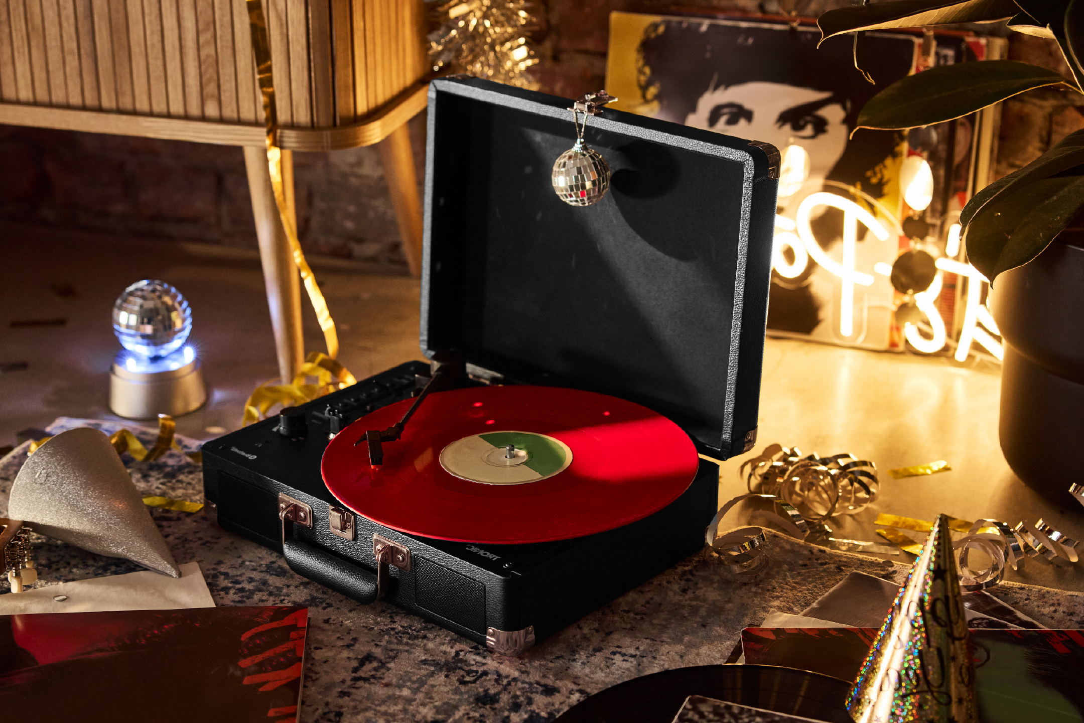 A black portable record player with a red vinyl record, surrounded by party decorations.
