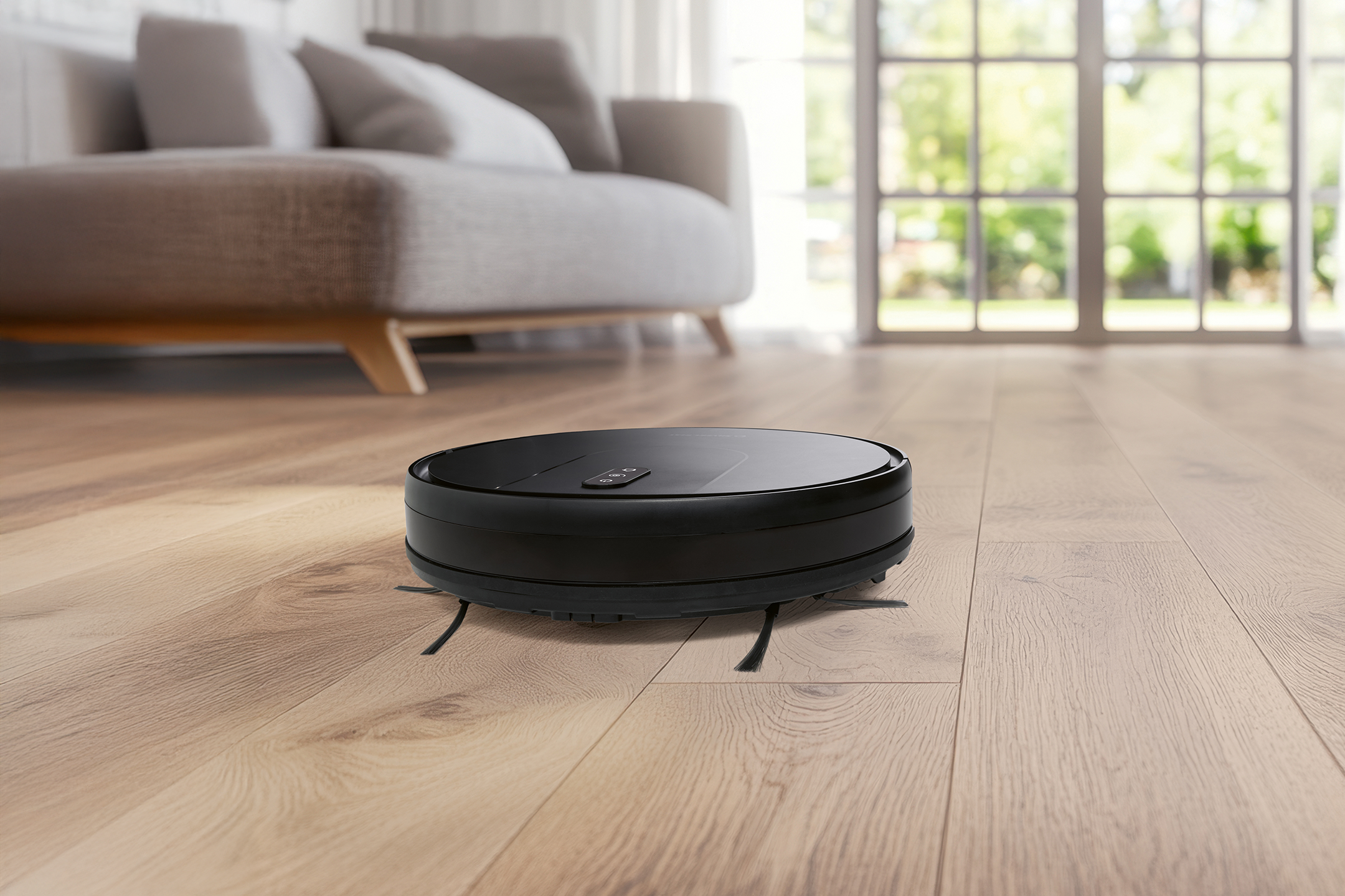 Black robot vacuum cleaner on a wooden floor in a modern living room.