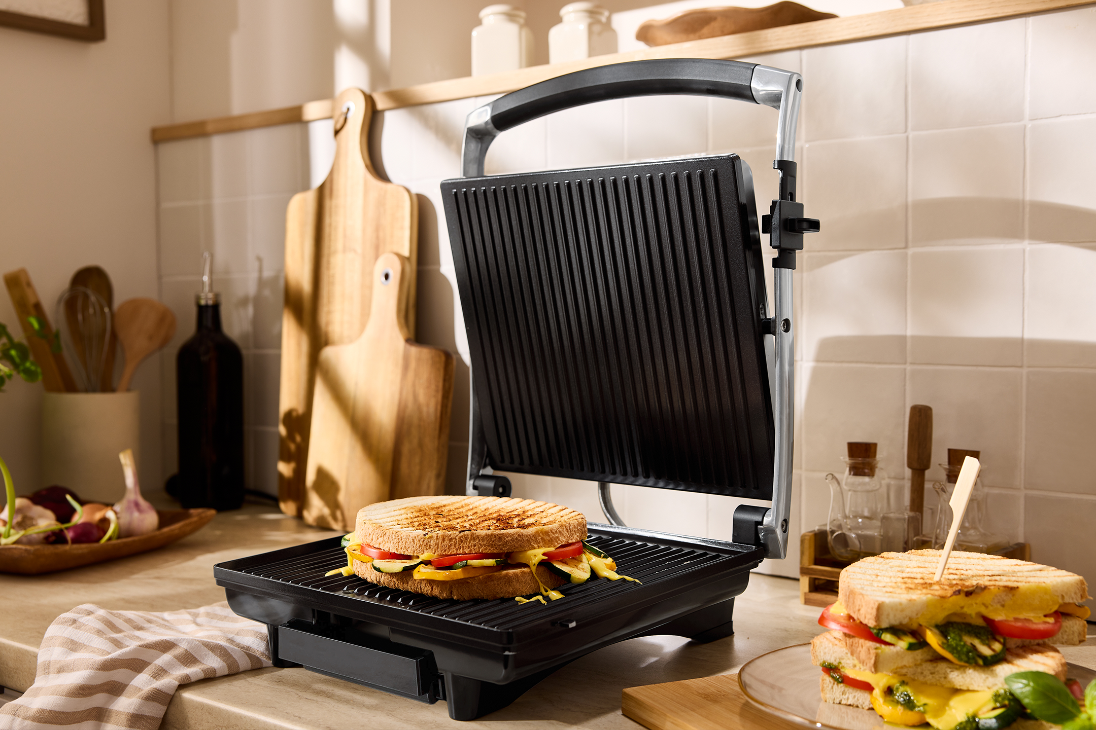 Toasted sandwich maker with a grilled cheese and vegetable sandwich in a kitchen