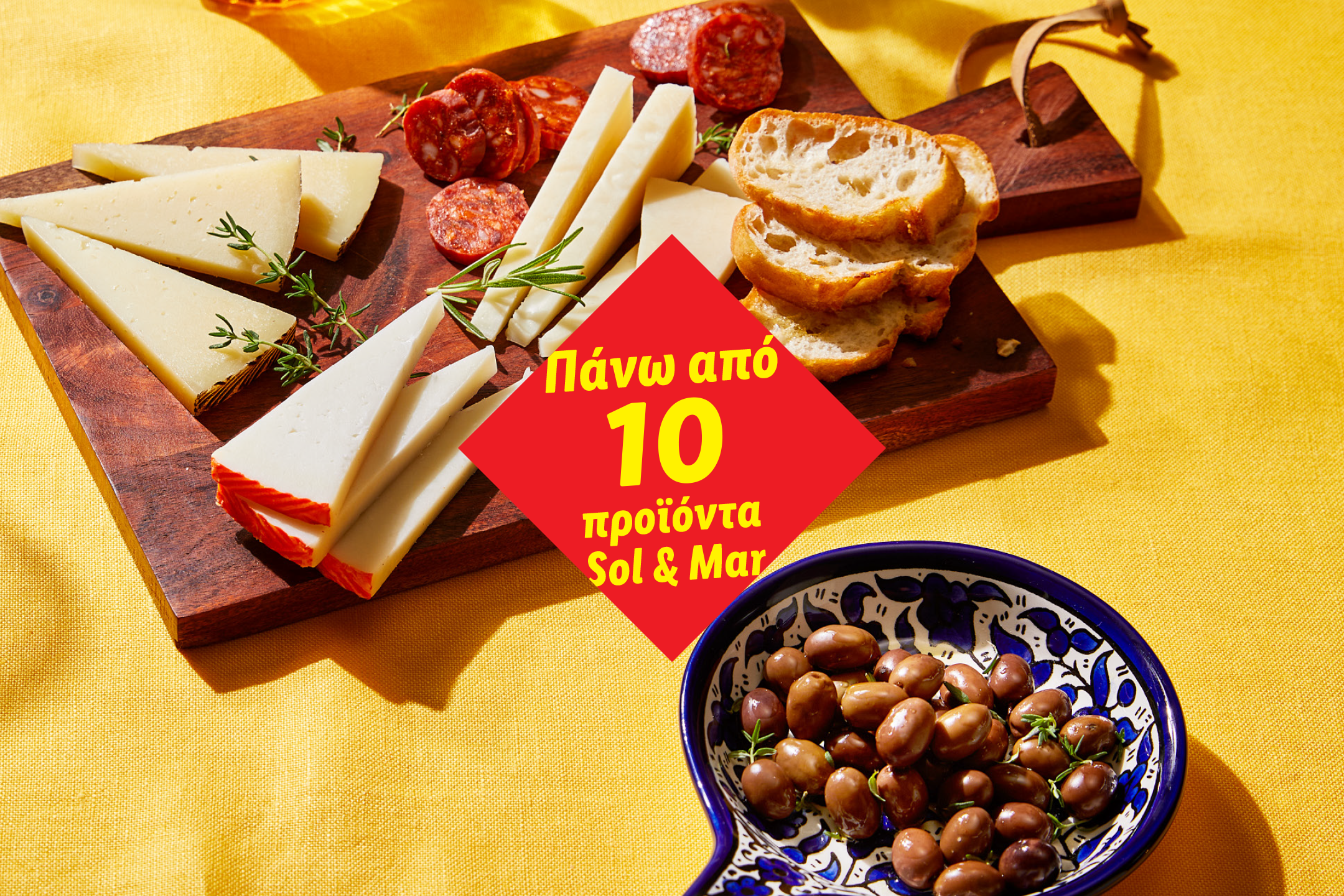 Πιατέλα τυριών και σαλαμιών με ψωμί και ελιές, με κόκκινο πανό που γράφει «Πάνω από 10 προϊόντα».