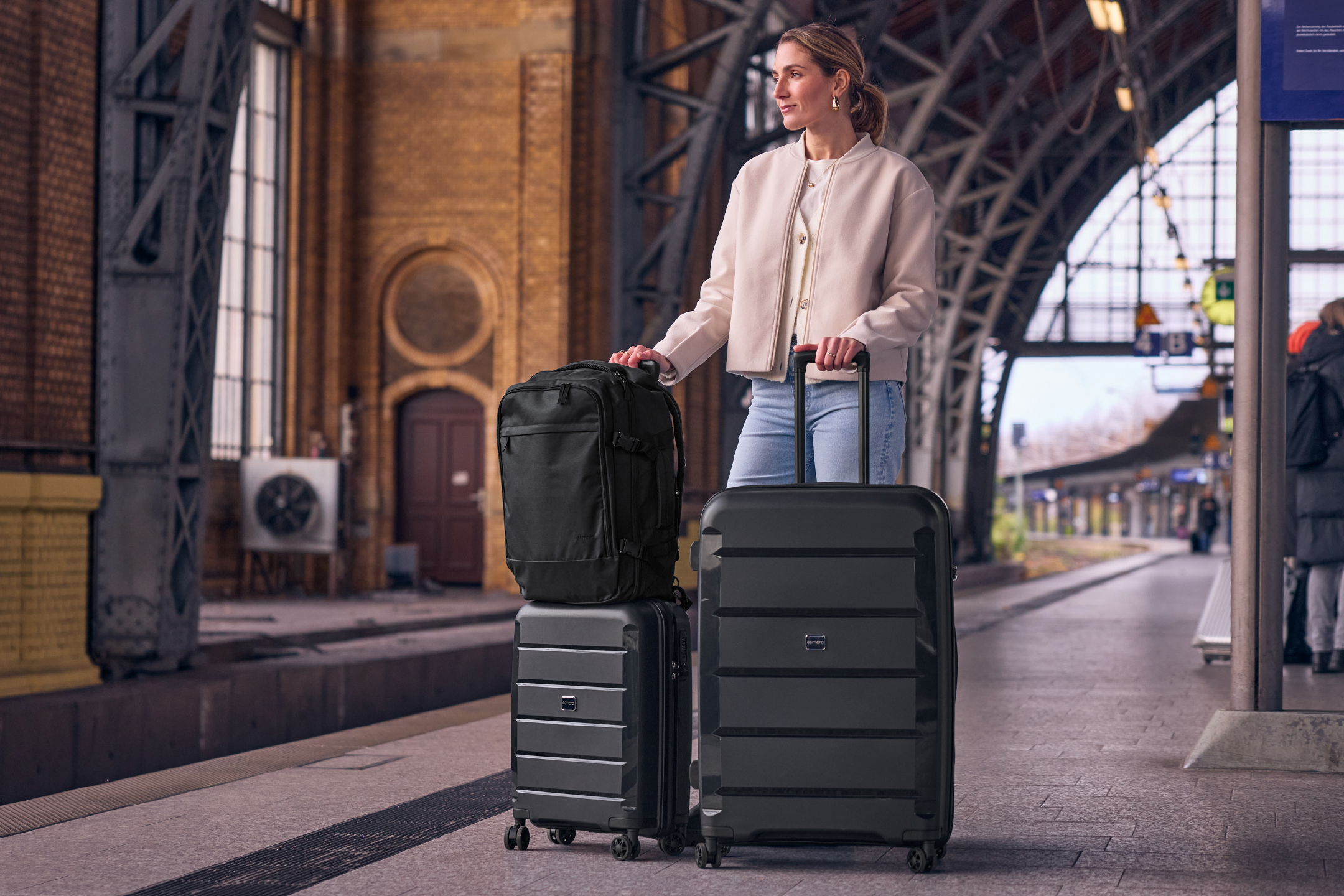 Γυναίκα με μαύρες αποσκευές και σακίδιο σε σιδηροδρομικό σταθμό