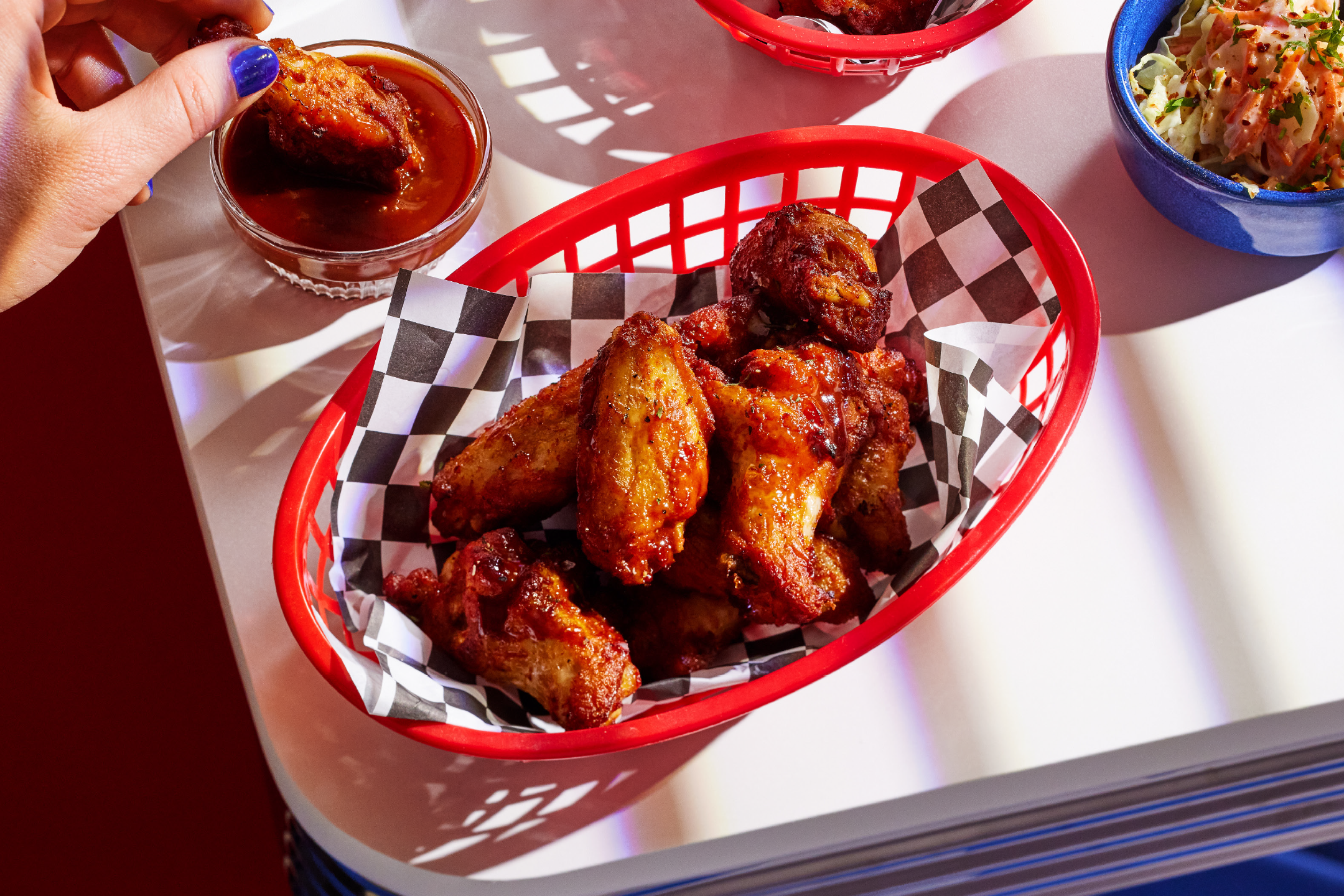 Τραγανές φτερούγες κοτόπουλου με σάλτσα και λάχανο σαλάτα σε λευκό τραπέζι