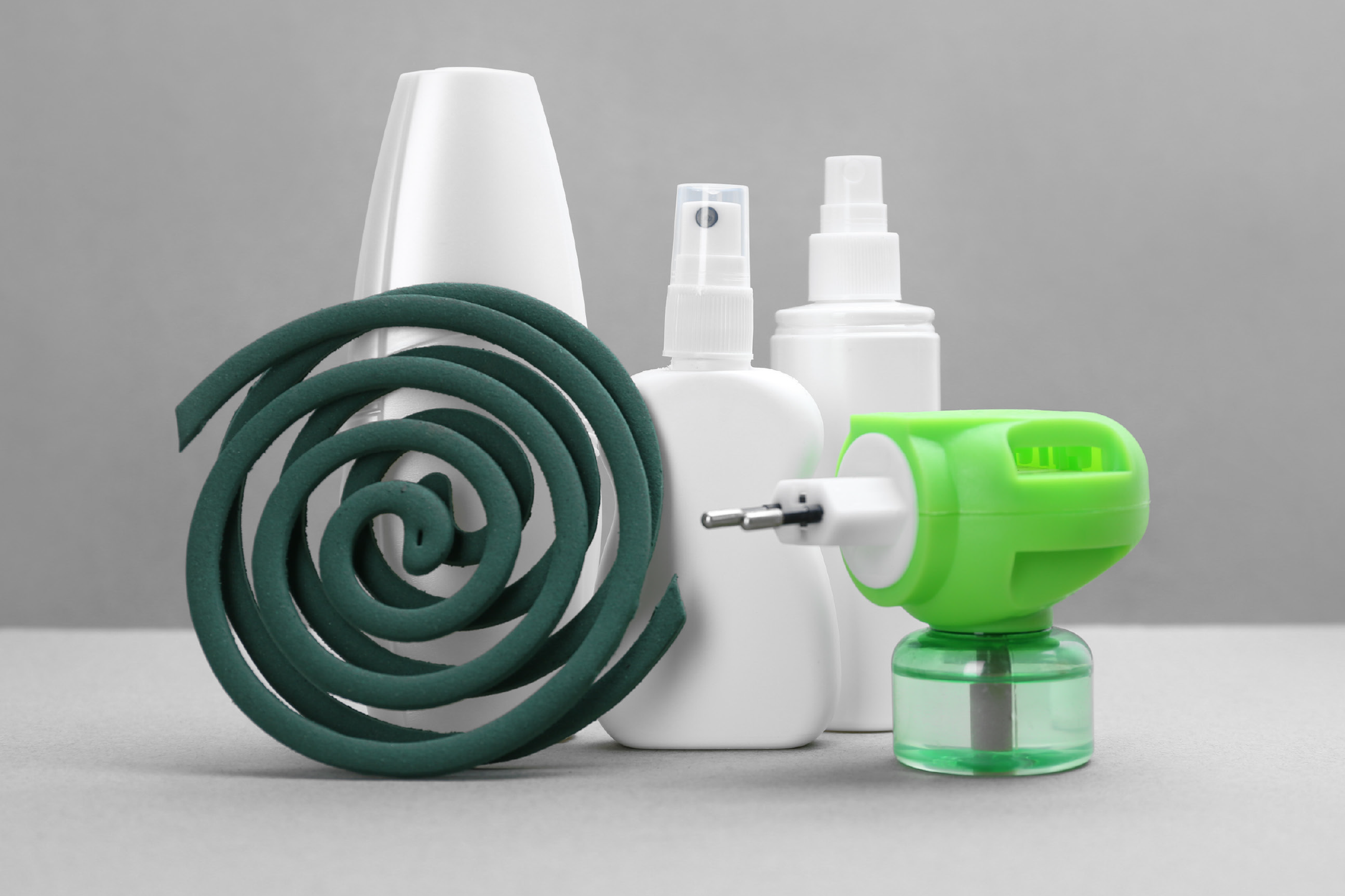 Mosquito repellent coil, sprays, and electric diffuser on a gray background.