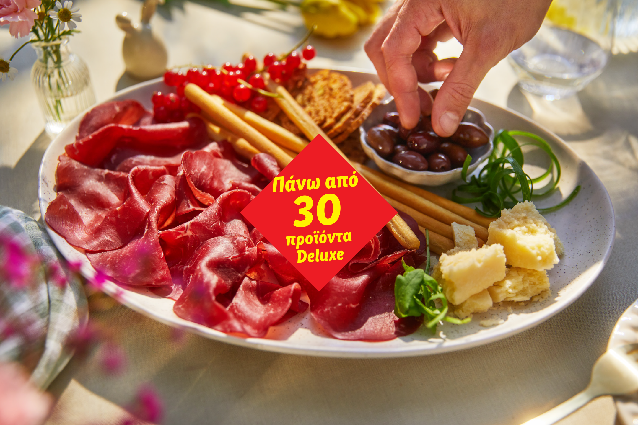 A platter with cured meats, olives, cheese, breadsticks, and red currants, with text 'Over 30 Deluxe products'.
