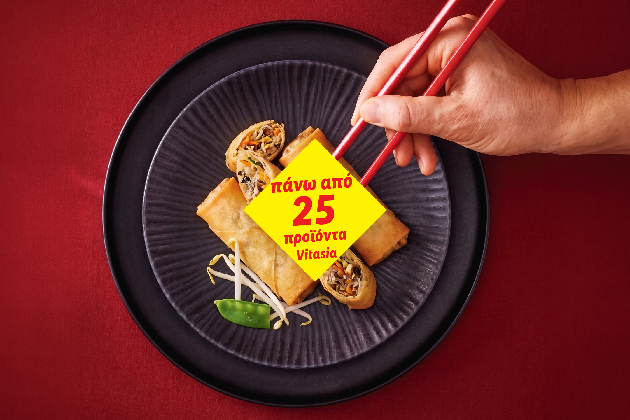 Χέρι κρατάει chopsticks πάνω από spring rolls σε μαύρο πιάτο, με κίτρινη ετικέτα