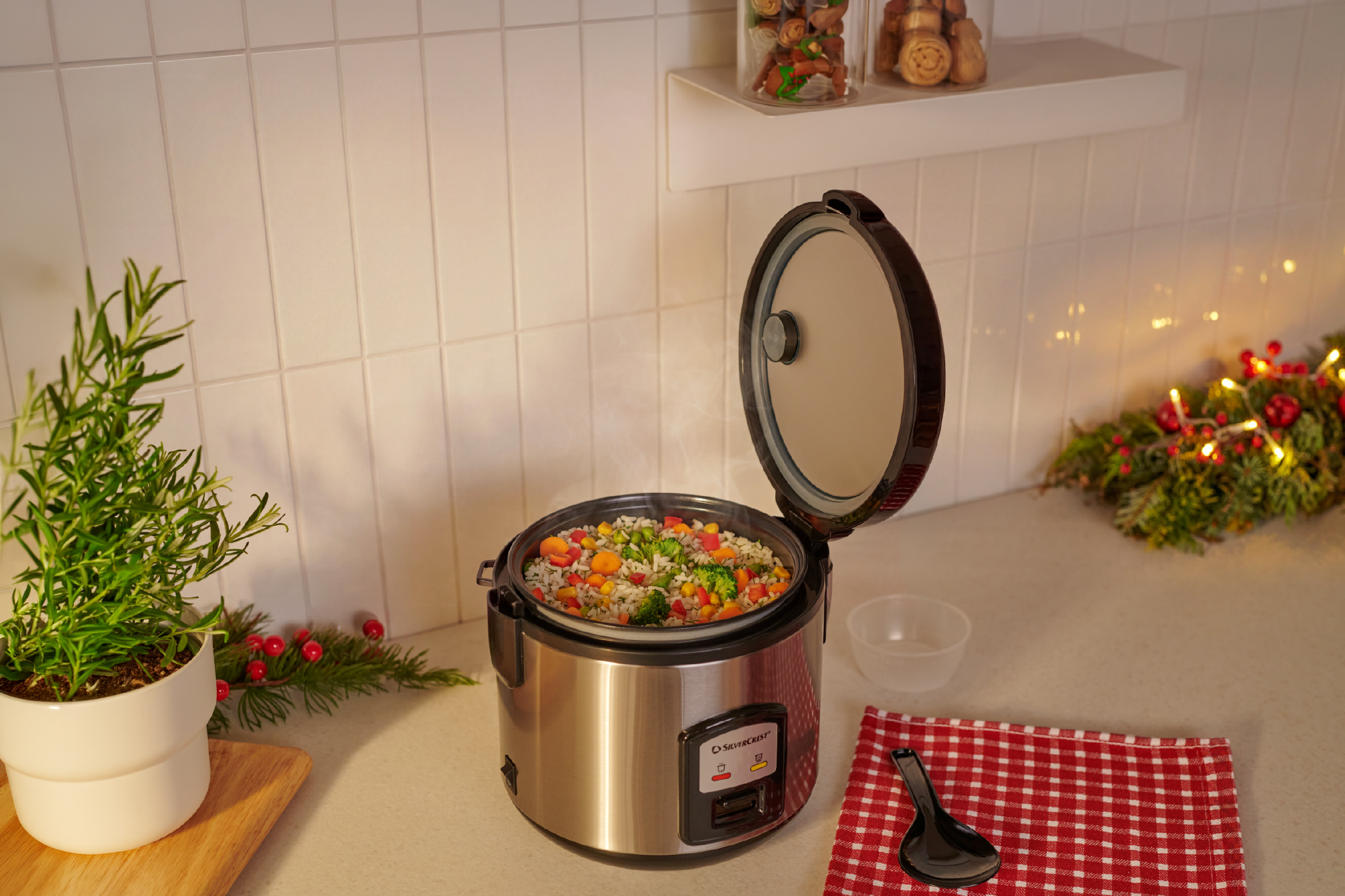 An open electric rice cooker with steamed rice and vegetables on a kitchen counter.