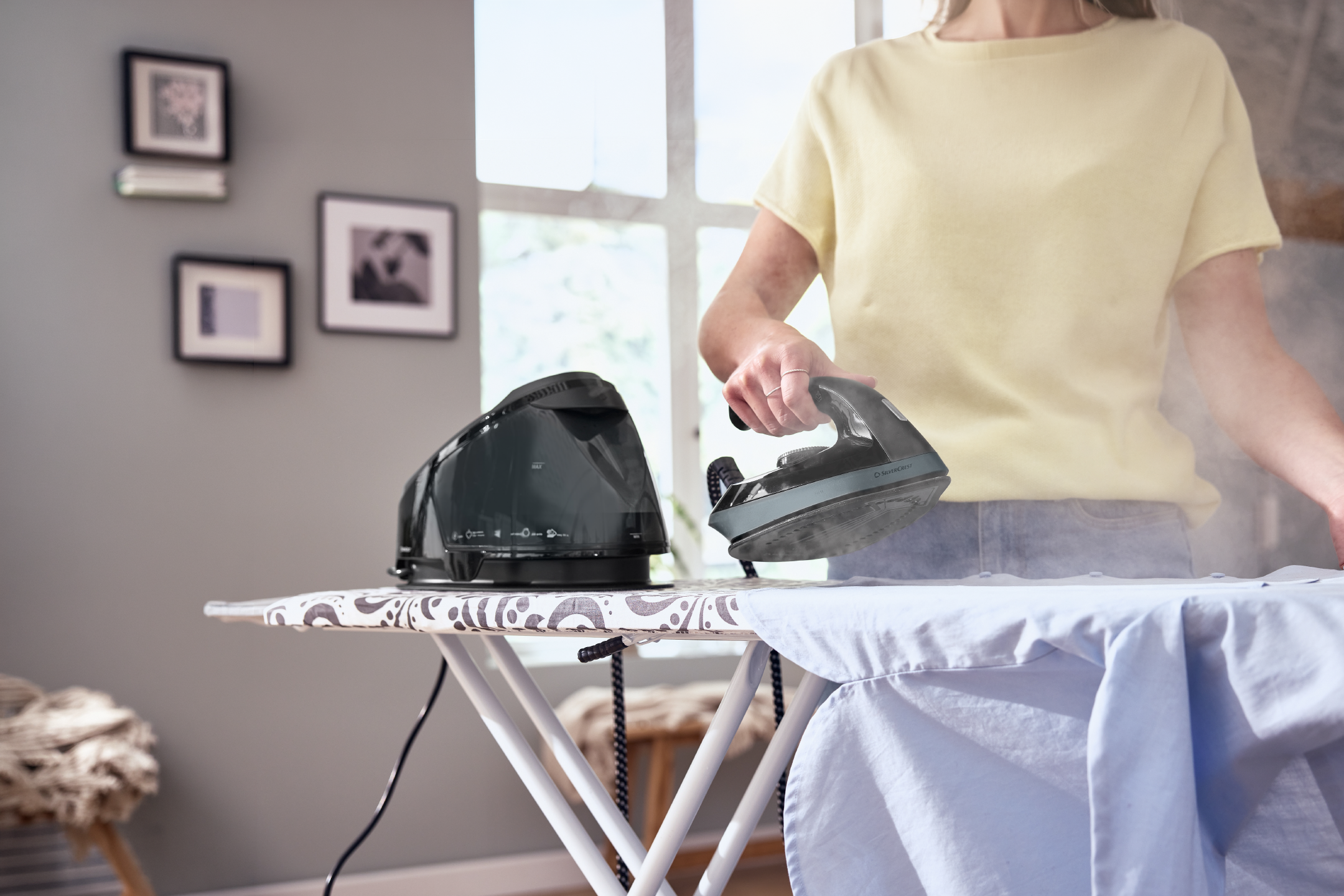 A steam generator iron on an ironing board with steam coming out of the soleplate.