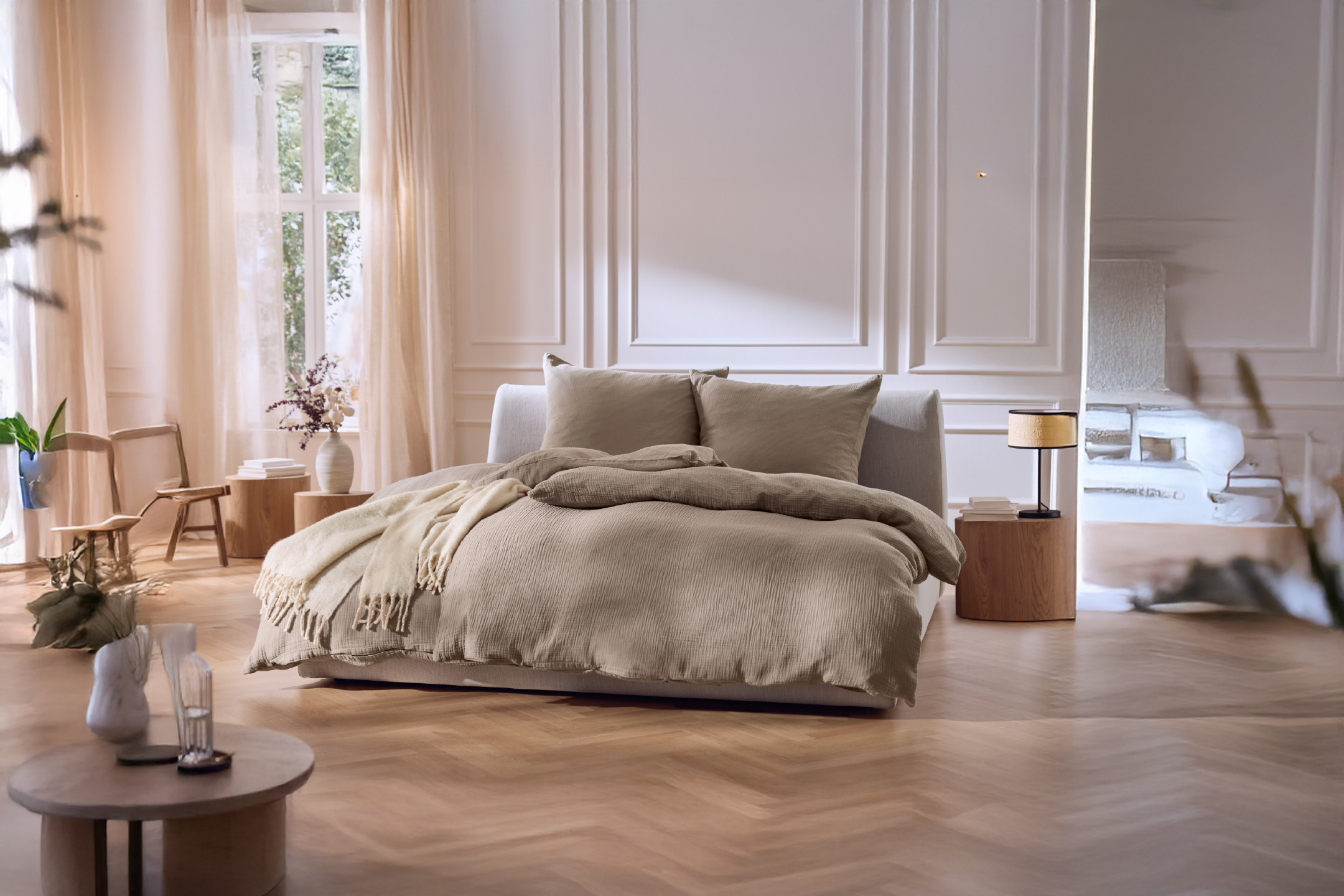 Υπνοδωμάτιο με κρεβάτι με μπεζ κλινοσκεπάσματα, ξύλινα έπιπλα και διάφανες κουρτίνες.