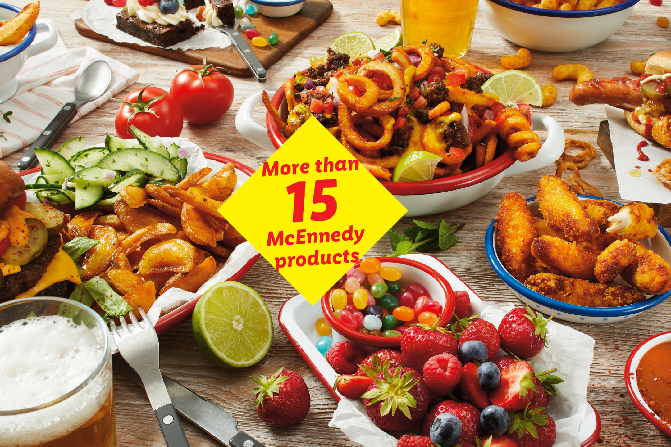 A table laden with various fast food items, including curly fries, burgers, hot dogs, chicken nuggets, and desserts, with a yellow sign saying 'More than 15 products'.
