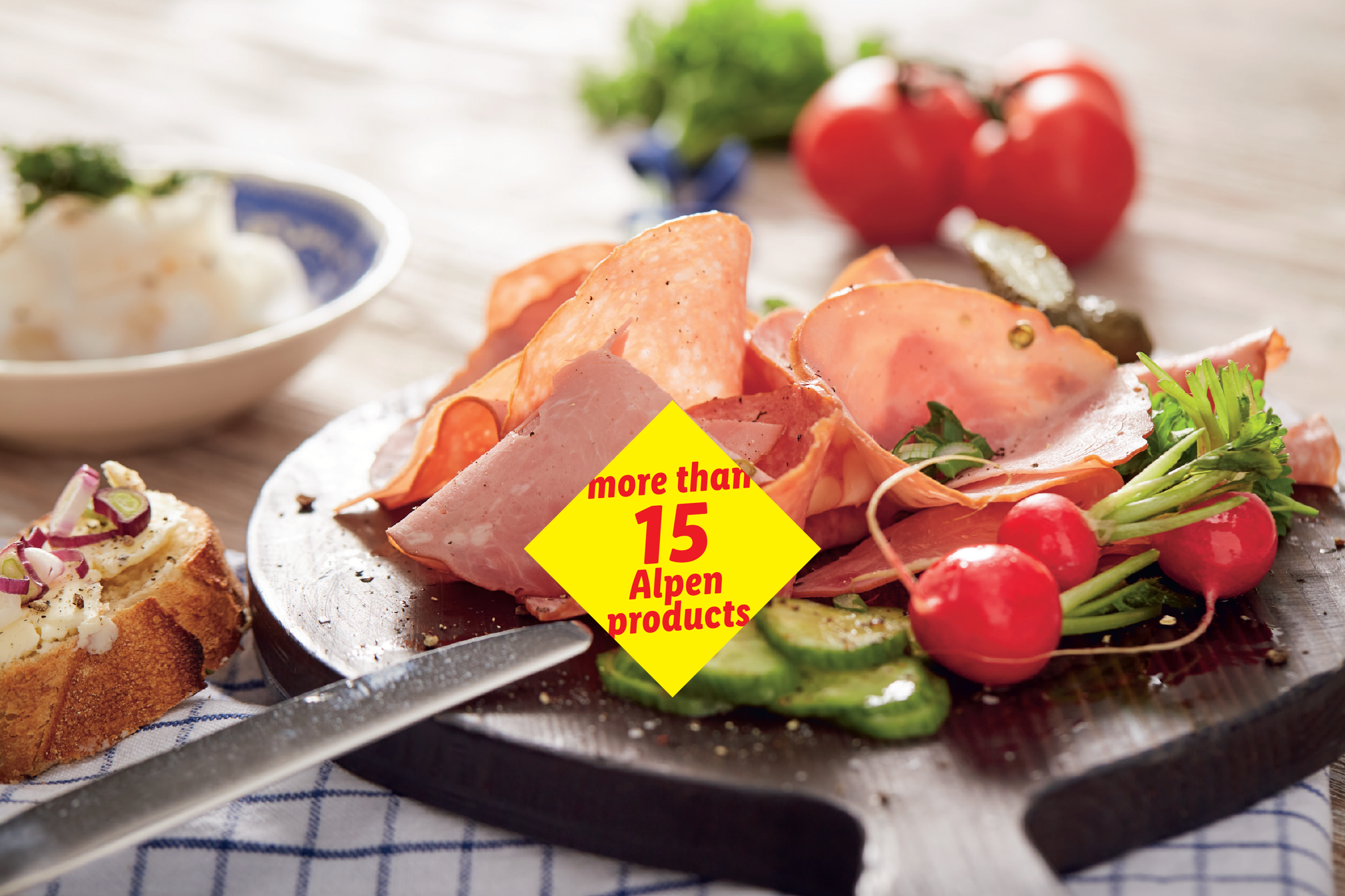 Platter with sliced cold cuts, radishes, cucumbers, and a bread slice, featuring a 'more than 15 Alpen products' label.