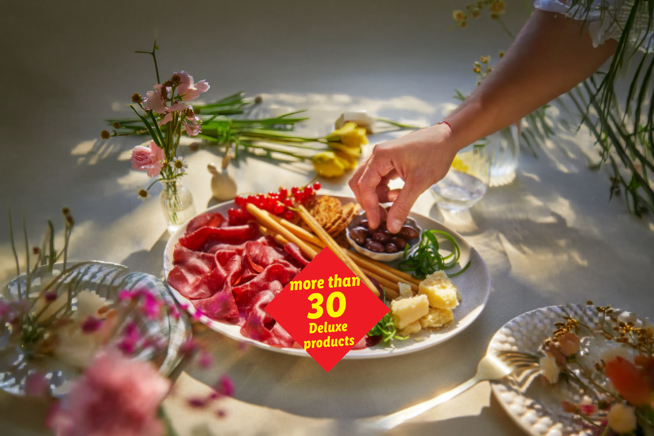 A charcuterie board with cured meats, cheese, olives, and breadsticks, with text 'more than 30 Deluxe products'.