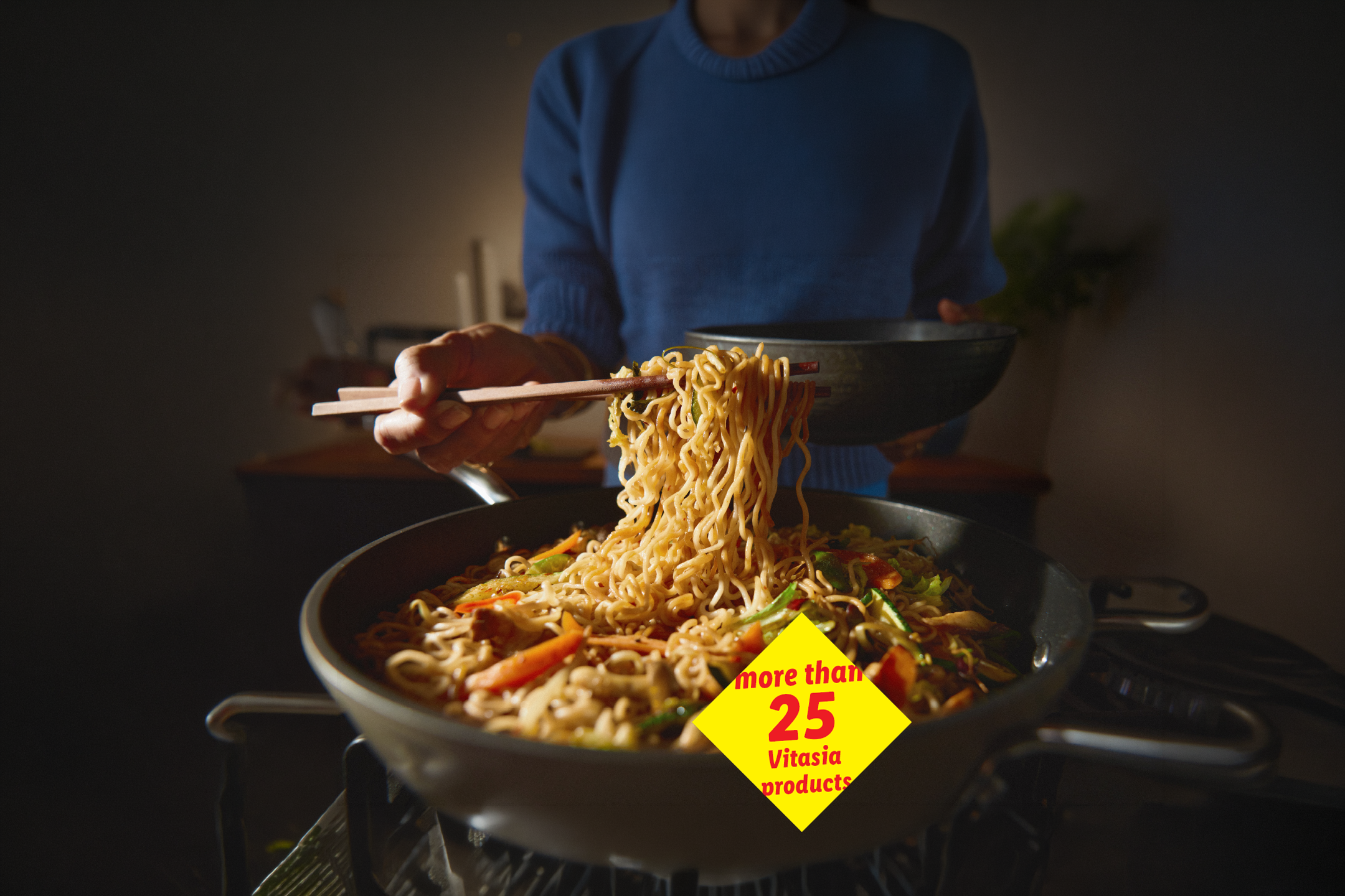 Person serving noodles with vegetables from a pan, with a yellow diamond highlighting 'more than 25 products'.