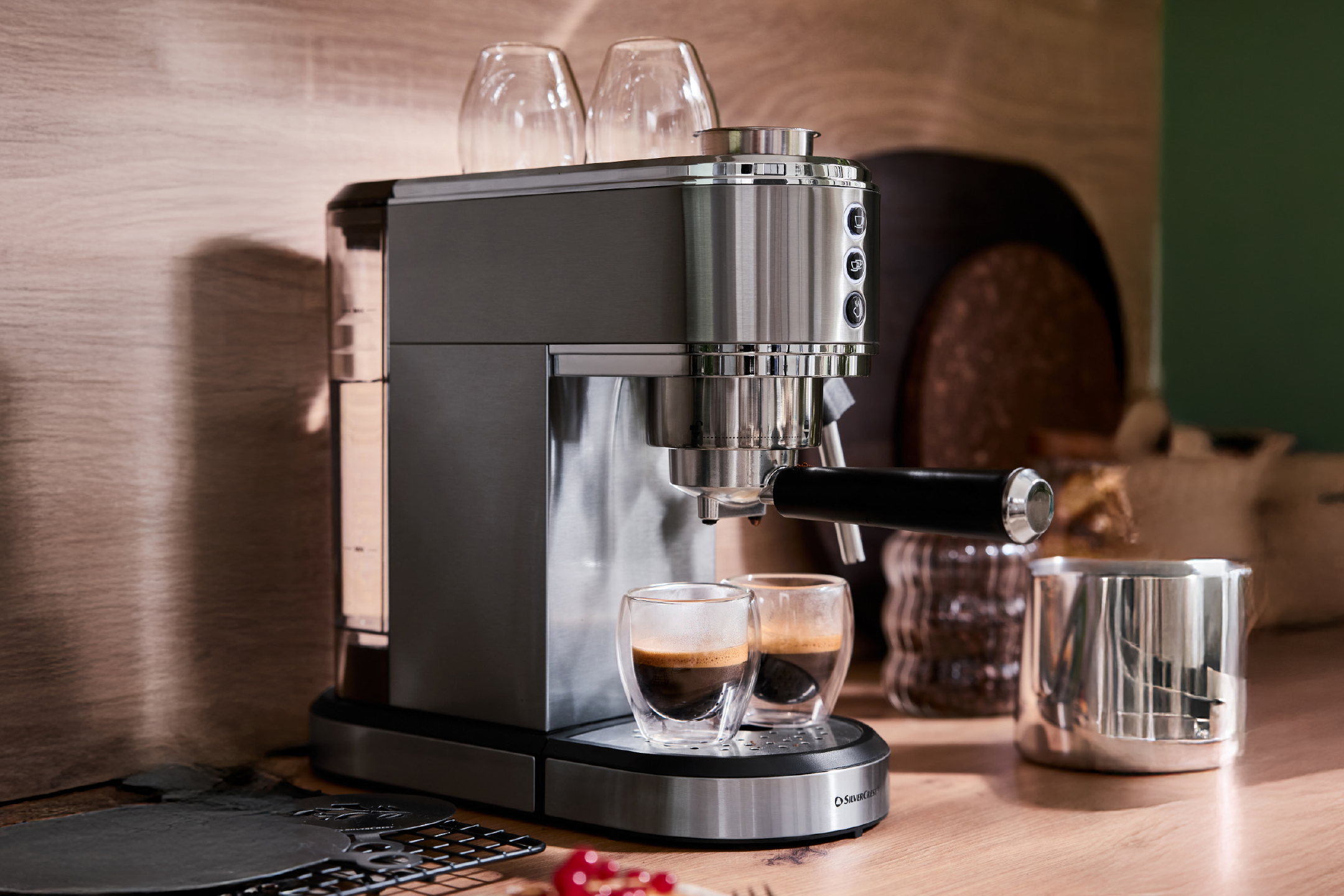 Espresso machine with two espresso shots in double-walled glasses on a wooden counter.