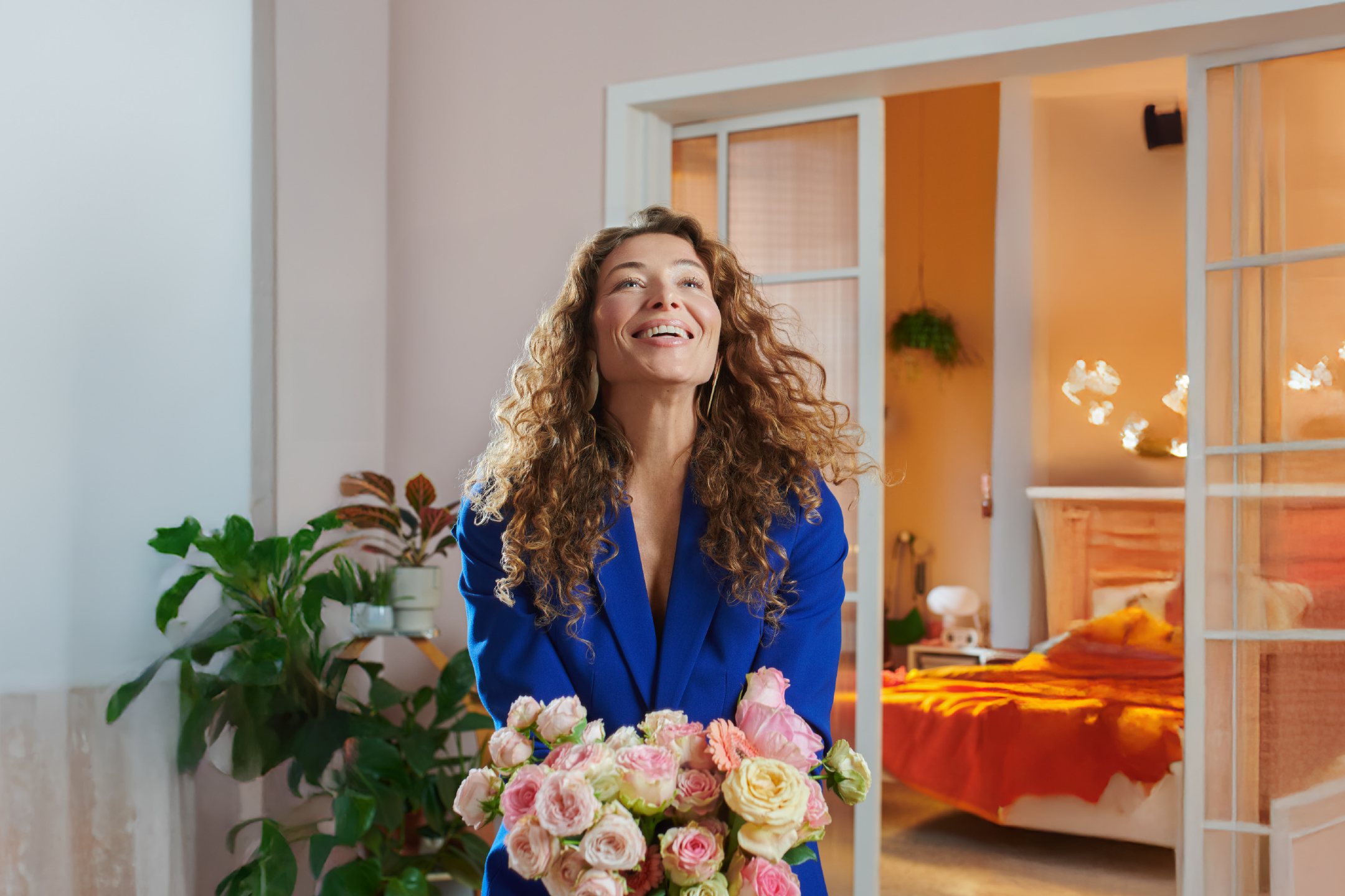 Woman in blue blazer holding a bouquet of pink and white roses, looking up and smiling.